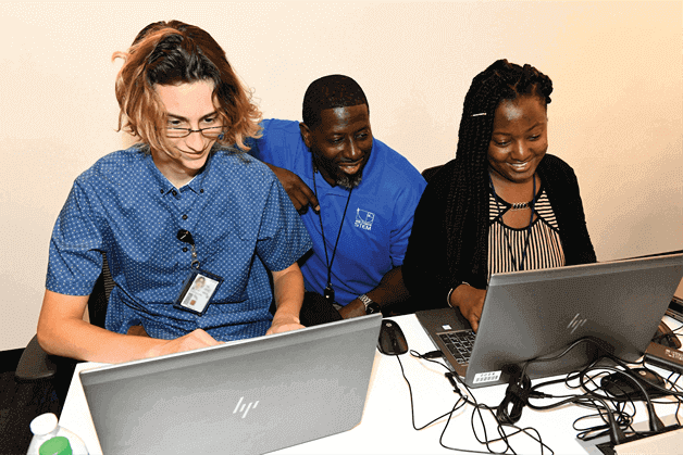Augustin Dantes Jr., 402nd Software Engineering Group technical advisor, center, observes as interns Alex Willis, left, and Jayania Young input code for an android app they are creating at Project Synergy July 28, 2021, in Warner Robins, Georgia.